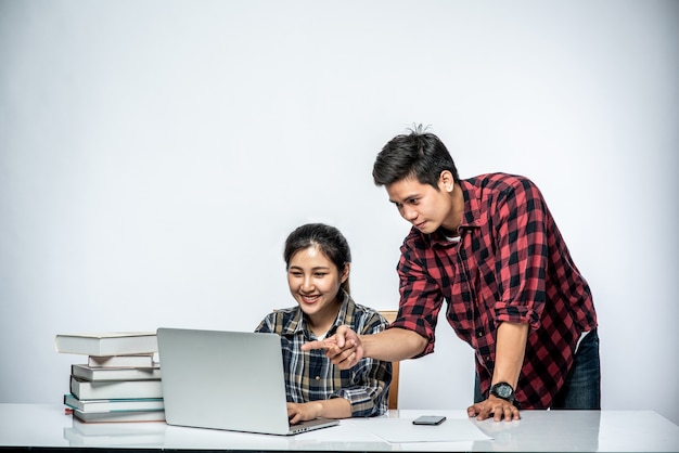 Los hombres enseñan a las mujeres cómo trabajar con computadoras portátiles en el trabajo.