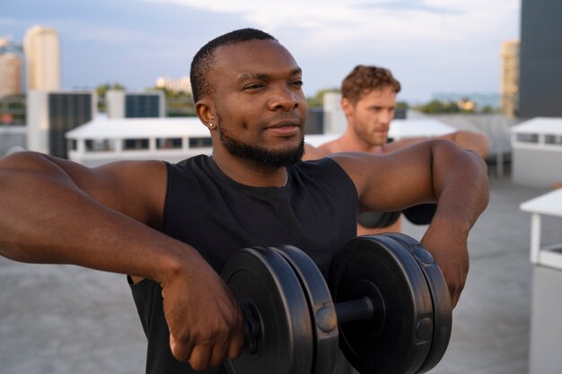 Hombres entrenando juntos al aire libre con pesas