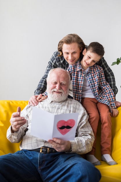 Foto gratuita hombres de familia de diferentes generaciones viendo tarjeta de regalo.