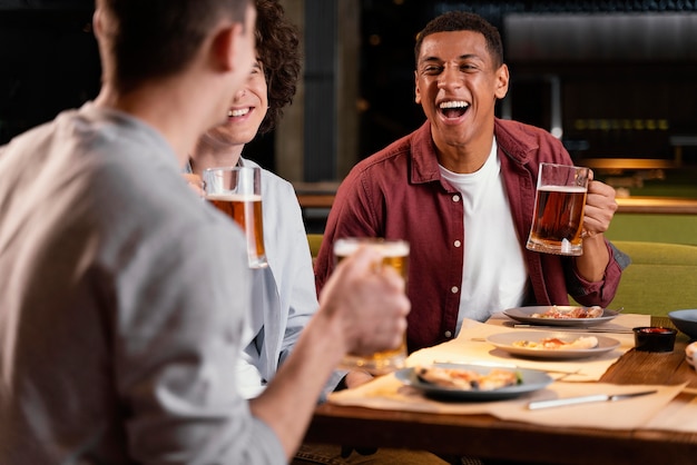 Foto gratuita hombres felices de primer plano con jarras de cerveza