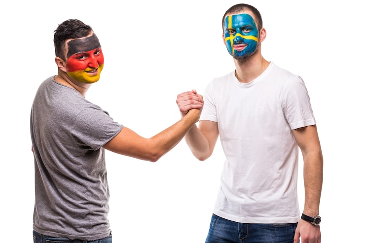 Foto gratuito hombres guapos partidarios leales fanáticos del equipo nacional de suecia y alemania con apretón de manos de cara de bandera pintada en blanco. fans de las emociones.
