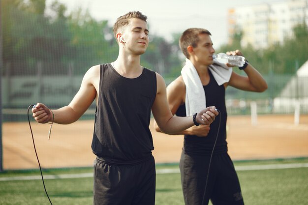 Hombres guapos en ropa deportiva de pie en un parque