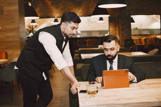 Hombres guapos en trajes negros, trabajando en un café