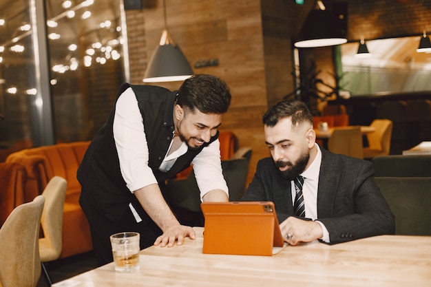 Hombres guapos en trajes negros, trabajando en un café