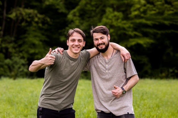 Hombres jovenes alegres que muestran la muestra de la excelencia en el claro