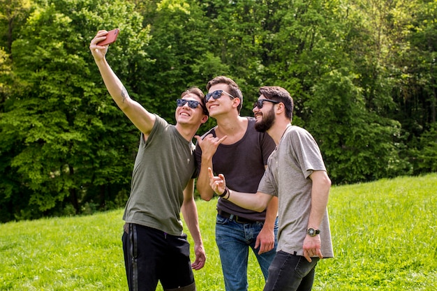 Hombres jovenes alegres que toman el selfie en naturaleza