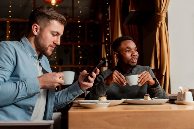 Hombres jóvenes bebiendo café juntos