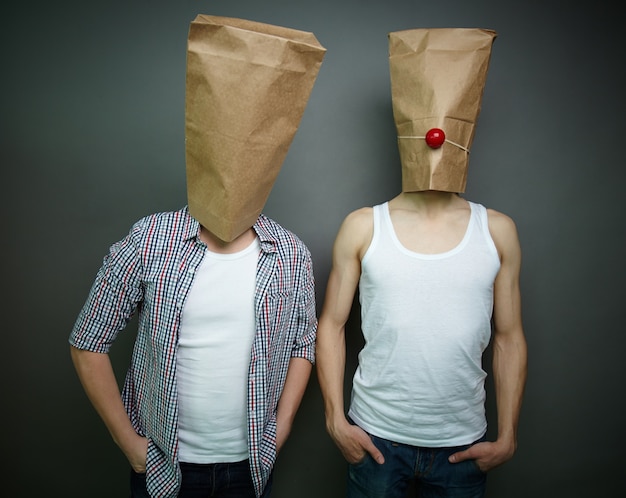 Foto gratuita hombres jóvenes con bolsas de papel sobre sus cabezas