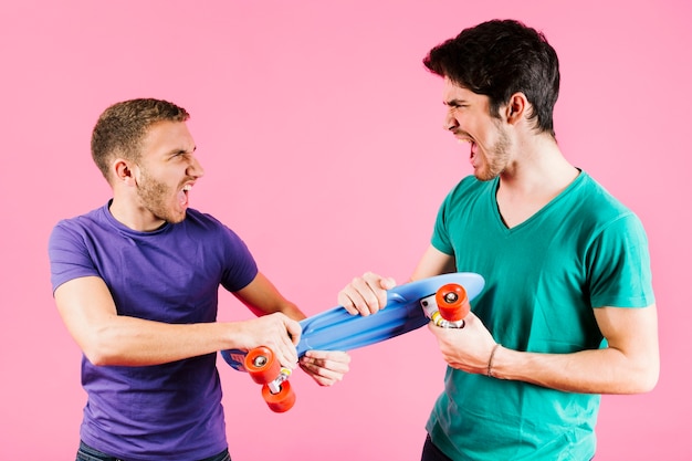 Hombres jóvenes compartiendo juguete longboard