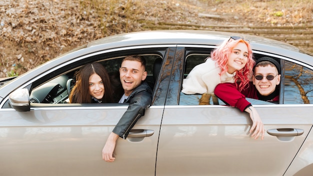 Hombres jóvenes y mujeres mirando por la ventana del coche