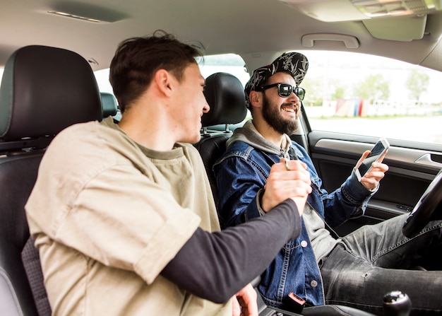 Hombres jóvenes saludándose en coche