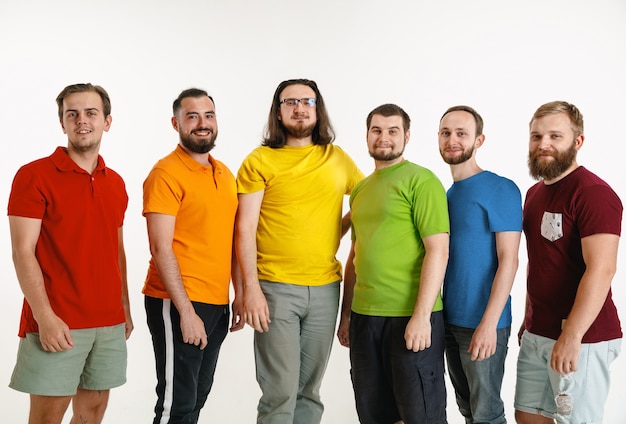 Los hombres jóvenes se vistieron con los colores de la bandera LGBT aislados en la pared blanca