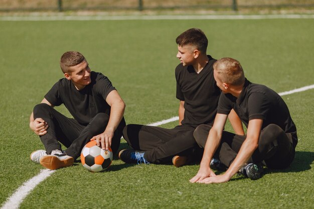 Los hombres juegan socer en el parque. Torneo de mini-fútbol. Chico en trajes deportivos negros.