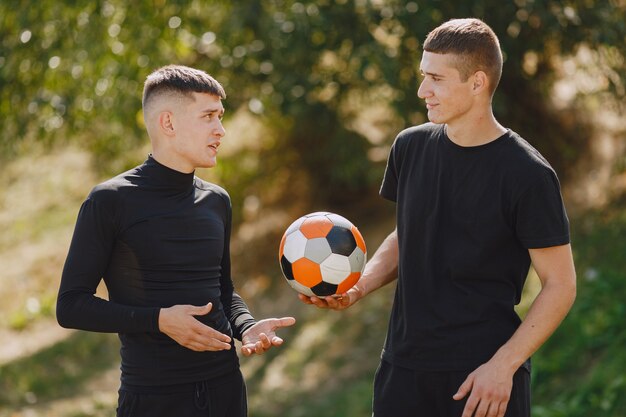 Los hombres juegan socer en el parque. Torneo de mini-fútbol. Chico en trajes deportivos negros.