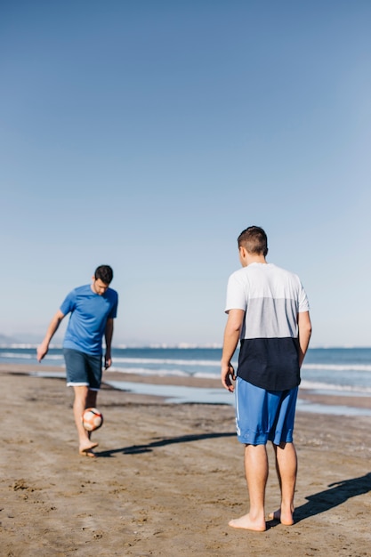 Hombres jugando al fútbol en la playa