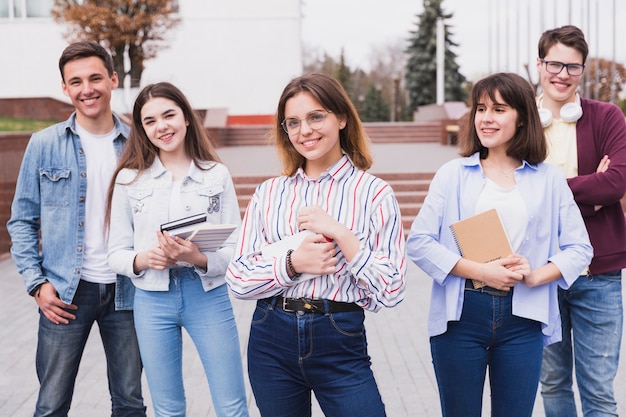 Foto gratuita hombres listos y mujeres inteligentes de pie con libros mirando a cámara