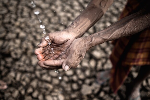 Los hombres mayores están expuestos al agua de lluvia en clima seco, el calentamiento global