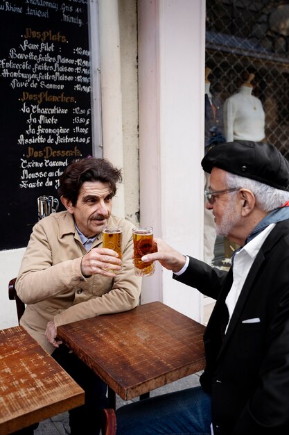 Hombres mayores de tiro medio con bebidas en bistro