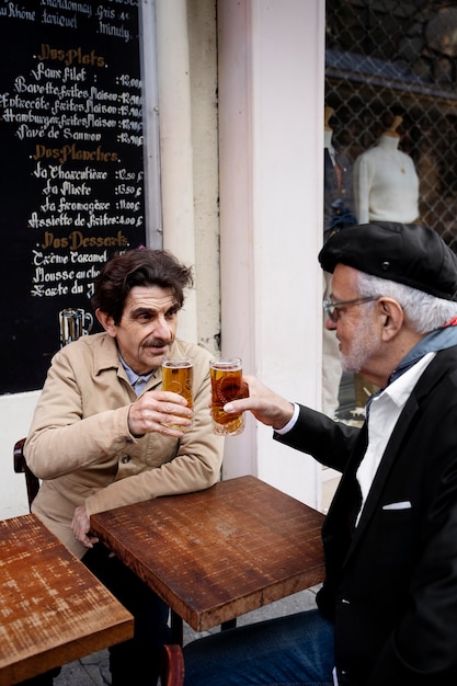 Hombres mayores de tiro medio con bebidas en bistro