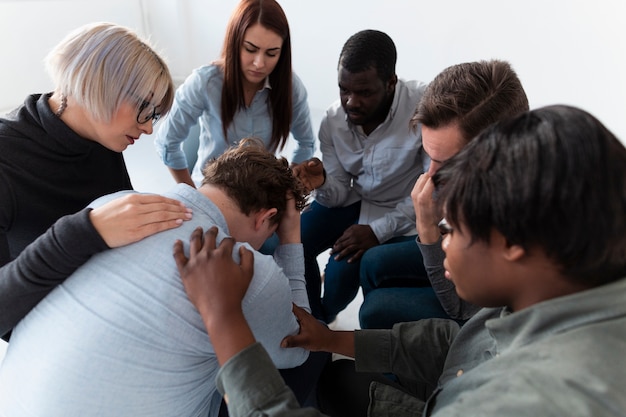 Hombres y mujeres consolando a un paciente triste