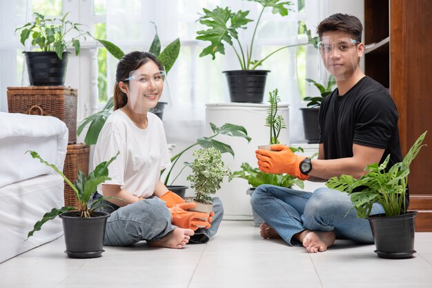 Hombres y mujeres con guantes naranjas se sentaron y plantaron árboles en una casa.