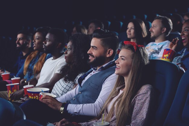 Hombres y mujeres jóvenes que pasan tiempo libre en el cine juntos
