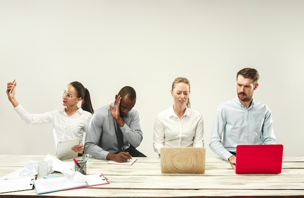 Hombres y mujeres jóvenes sentados en la oficina y trabajando en computadoras portátiles. Concepto de emociones