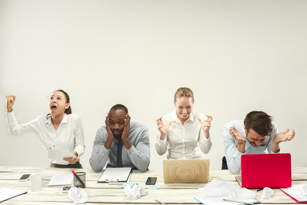 Hombres y mujeres jóvenes sentados en la oficina y trabajando en computadoras portátiles. Concepto de emociones