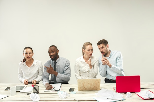 Foto gratuita hombres y mujeres jóvenes sentados en la oficina y trabajando en computadoras portátiles. concepto de emociones