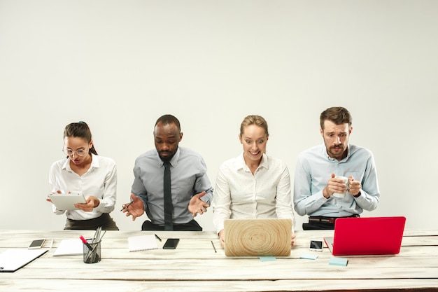 Hombres y mujeres jóvenes sentados en la oficina y trabajando en computadoras portátiles. Concepto de emociones