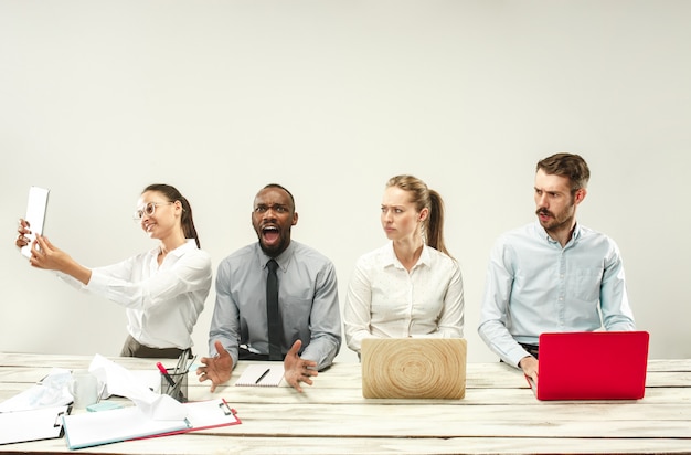 Hombres y mujeres jóvenes sentados en la oficina y trabajando en computadoras portátiles. Concepto de emociones