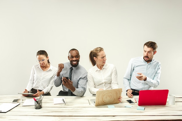 Hombres y mujeres jóvenes sentados en la oficina y trabajando en computadoras portátiles. Concepto de emociones