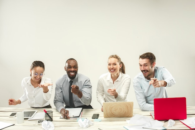 Hombres y mujeres jóvenes sentados en la oficina y trabajando en computadoras portátiles. Concepto de emociones