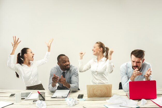 Hombres y mujeres jóvenes sentados en la oficina y trabajando en computadoras portátiles. Concepto de emociones