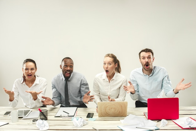 Hombres y mujeres jóvenes sentados en la oficina y trabajando en computadoras portátiles. Concepto de emociones