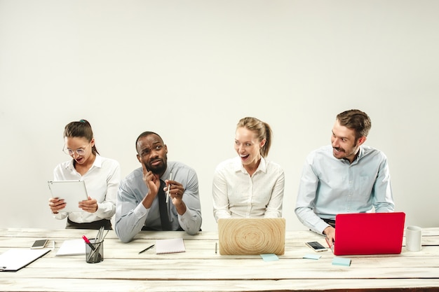 Hombres y mujeres jóvenes sentados en la oficina y trabajando en computadoras portátiles.