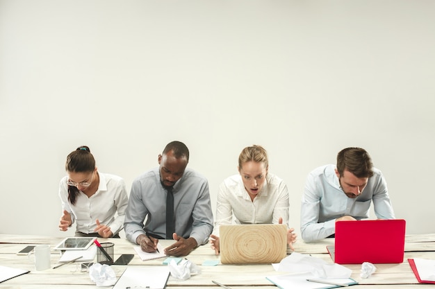Hombres y mujeres jóvenes sentados en la oficina y trabajando en computadoras portátiles.