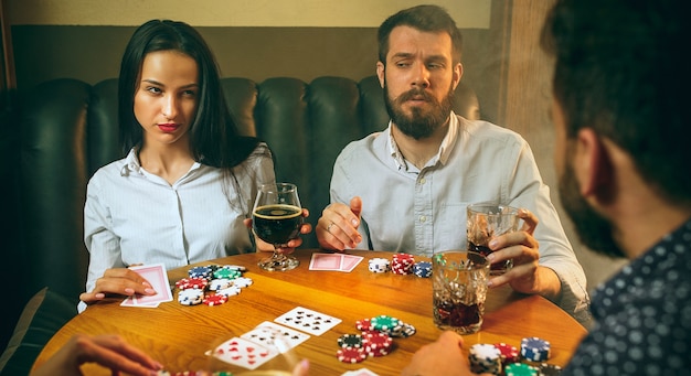 Hombres y mujeres jugando al juego de cartas. Poker, entretenimiento nocturno y concepto de emoción.