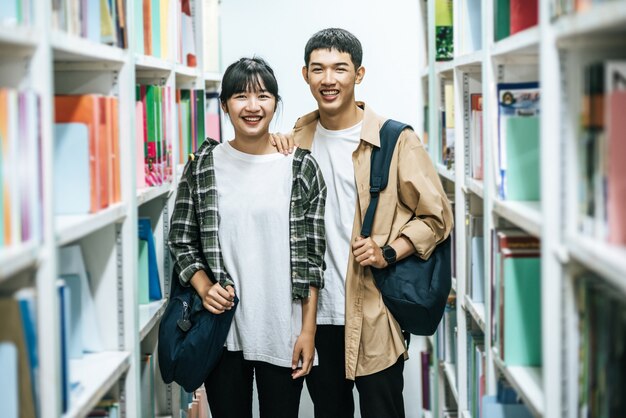 Hombres y mujeres llevando una mochila y buscando libros en la biblioteca.