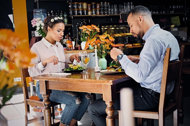 Hombres y mujeres negros americanos comiendo comida vegana en un restaurante.