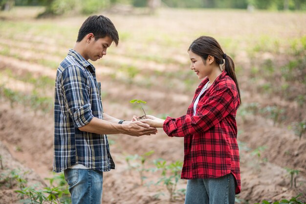 Hombres y mujeres de pie y sosteniendo árboles jóvenes.