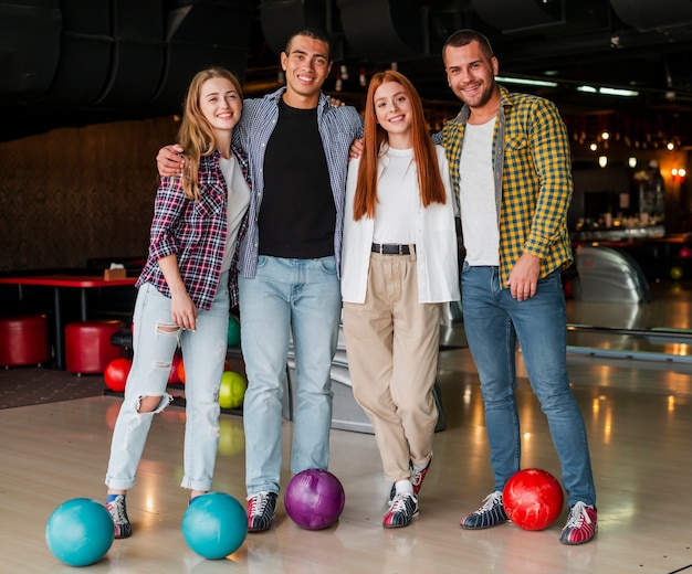 Foto gratuita hombres y mujeres posando en un club de bolos