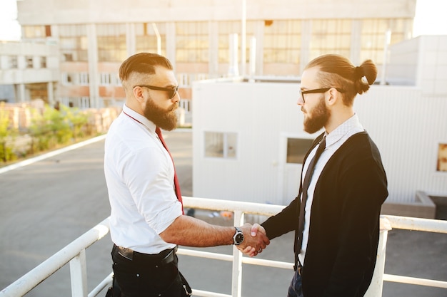 Hombres de negocios dándose la mano en unas escaleras