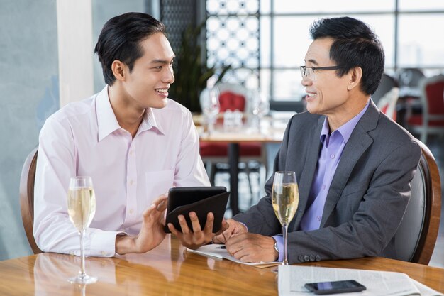 Los hombres de negocios felices discuten proyecto en el restaurante