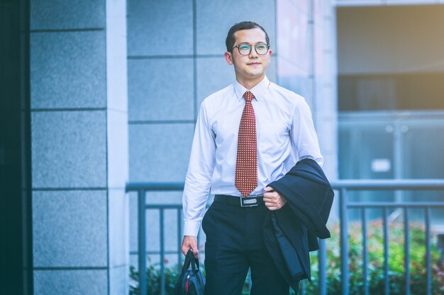 Los hombres de negocios llevan ordenadores portátiles para trabajar en la entrada de un edificio de oficinas