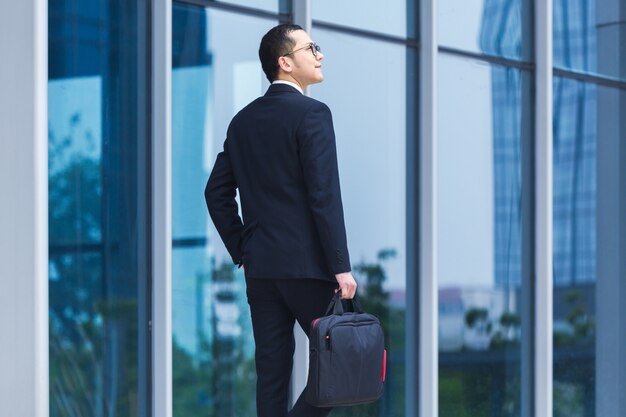 Los hombres de negocios llevan ordenadores portátiles para trabajar en la entrada de un edificio de oficinas