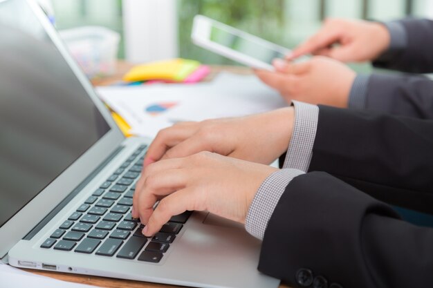 Hombres de negocios con un portátil y una tablet visto desde un lado