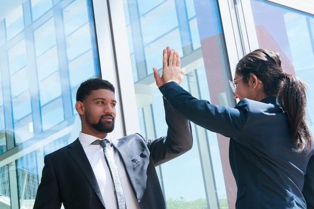 Foto gratuita hombres de negocios positivos alto fiving al aire libre