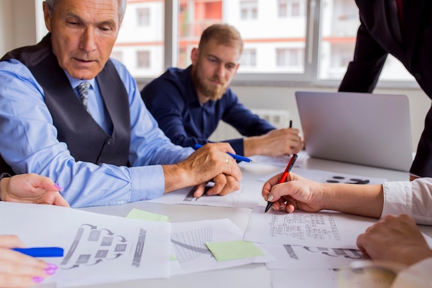 Hombres de negocios que discuten las tablas y los gráficos en la tabla en la reunión