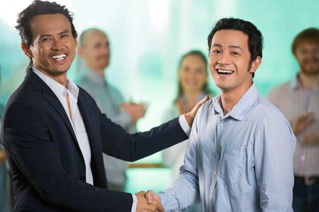 Los hombres de negocios que sacuden las manos y que celebra éxito